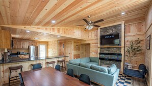 A wooden cabin interior with a dining area, sofa, and kitchen.
