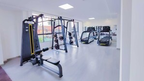 Ein Fitnessstudio mit Laufbändern, Krafttrainingsgeräten und großen Fenstern.