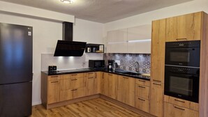 A modern kitchen with wooden cabinets, a black refrigerator, a built-in microwave, and a double oven.