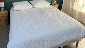 Une chambre à coucher avec un lit, des poutres en bois, un appareil de climatisation et une table de chevet avec une lampe.