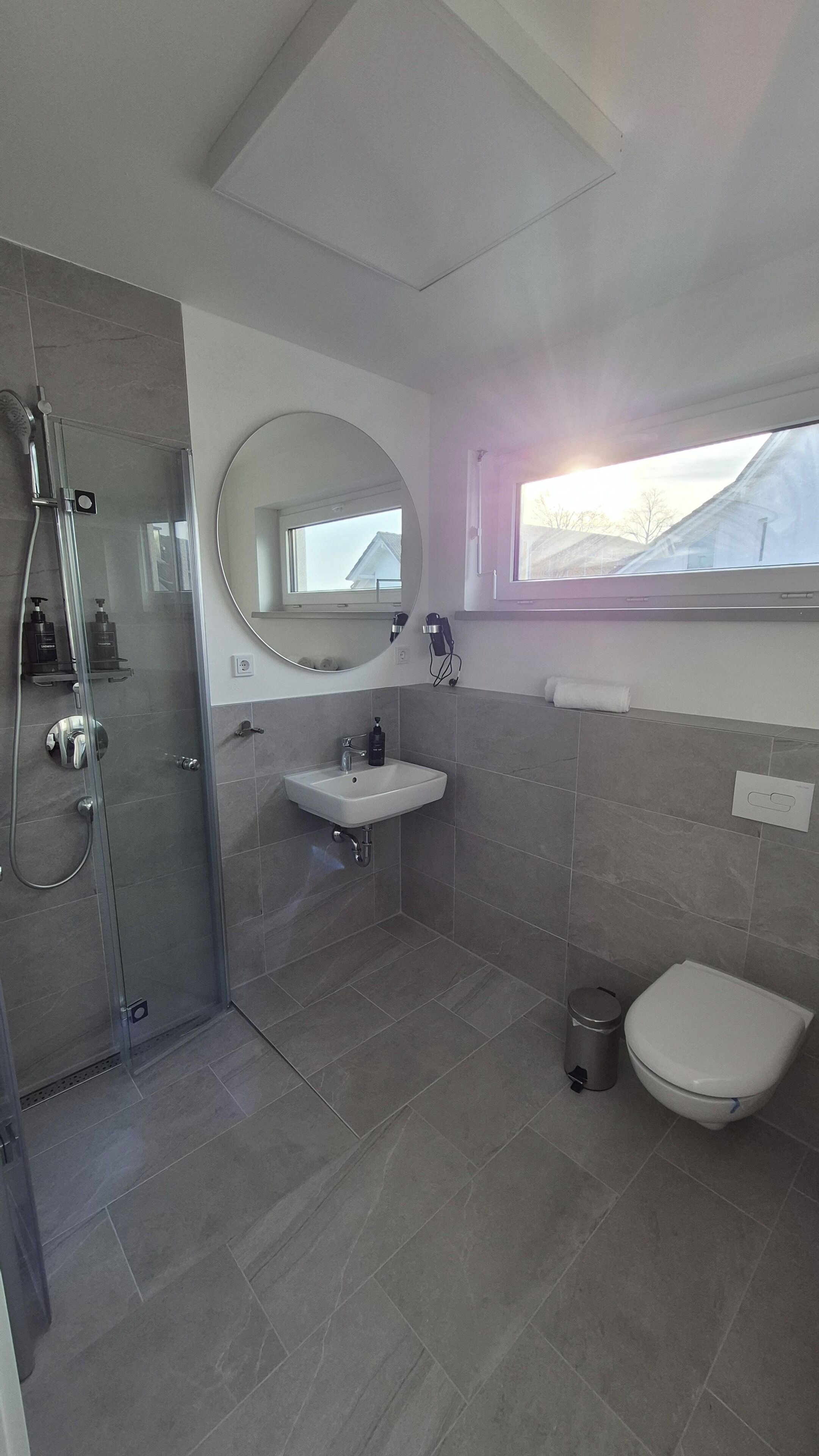 Ein modernes Badezimmer mit einer einteiligen Duschkabine, einem weißen Waschbecken und einer Toilette.