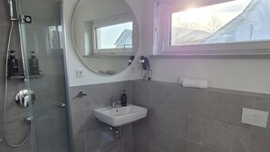 Ein modernes Badezimmer mit einer einteiligen Duschkabine, einem weißen Waschbecken und einer Toilette.
