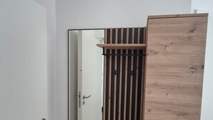 Ein Zimmer mit einem Holzschrank, einem Spiegel und einer Tür.