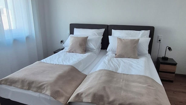 Ein Doppelbett mit schwarzem Kopfteil, zwei Nachttische und eine Deckenleuchte.