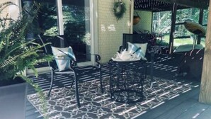 Un espace extérieur aménagé avec des sièges, protégé par un auvent, comprenant un tapis à motifs, des chaises et une table.