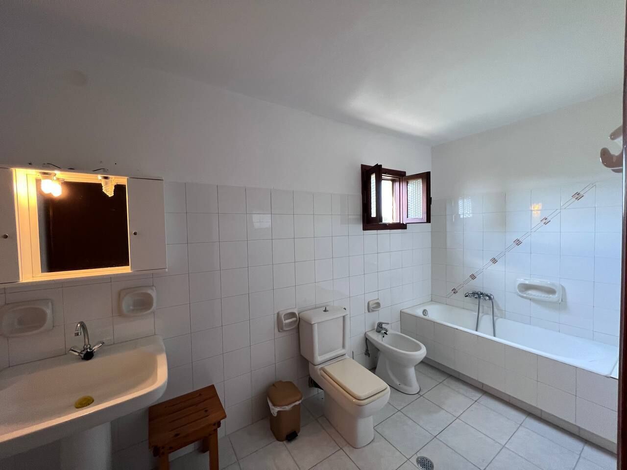 Een badkamer met een wastafel, toilet, bidet en bad.