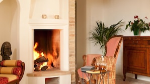 Una sala acogedora con chimenea, un sillón cómodo, un aparador de madera y una planta en maceta.