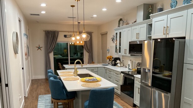 A modern kitchen with a central island, stainless steel appliances, and blue chairs.