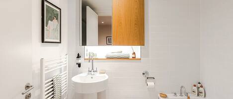 A modern bathroom with a white sink, a toilet, and a bathtub.