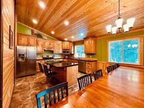 Un'ampia cucina con mobili in legno, un'isola grande e un'area pranzo con un tavolo lungo.