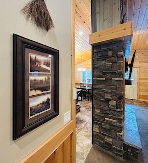 A framed photograph on the wall, a stone pillar, and a wooden ceiling.
