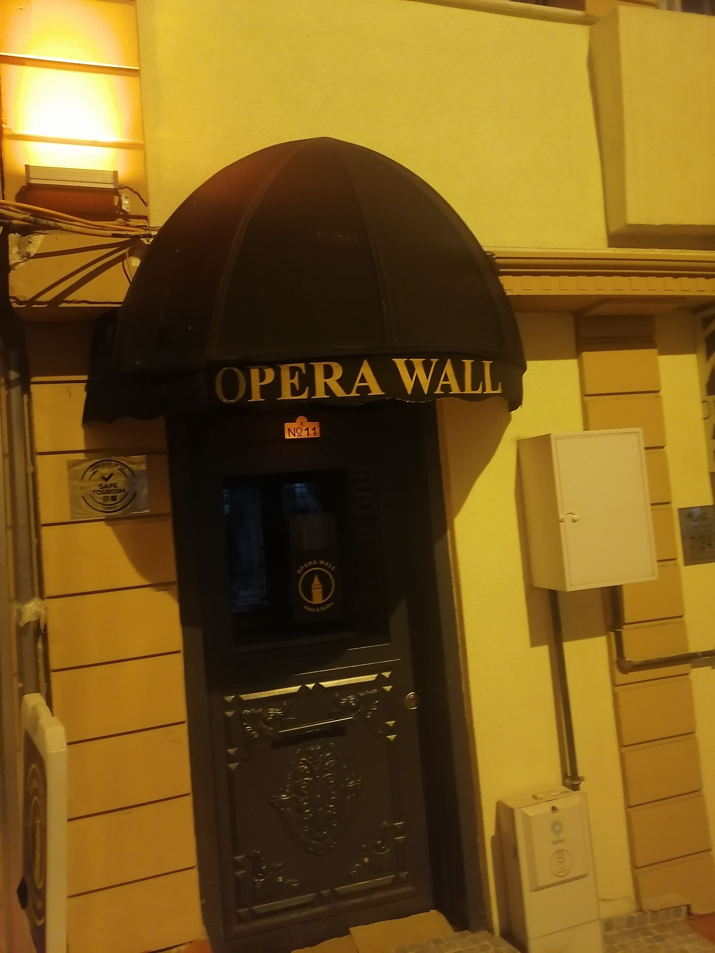A black entrance with "OPERA WALL" signage, a safe tourism sign, and a utility box.