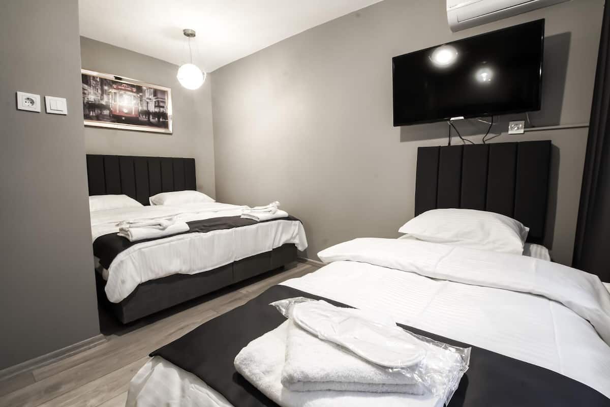 Una habitación de hotel moderna con dos camas, un televisor de pantalla plana y un aire acondicionado instalado en la pared.