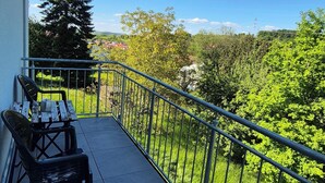 A balcony with a view of a green landscape, a metal railing, and two black chairs. - Apartments Seibel double/twin room with balcony (Reutlingen)