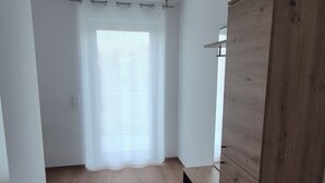 A room with a wooden wardrobe, a ceiling fan, and a window with sheer curtains. - Apartments Seibel double/twin room with balcony (Reutlingen)