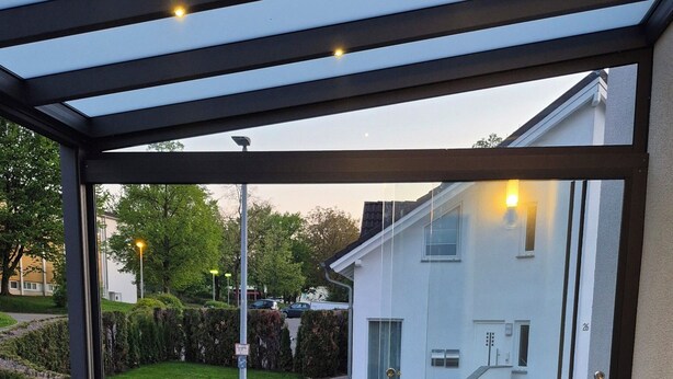 An outdoor patio with a sofa, a table, and a railing.