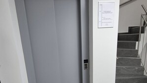 A modern elevator with a control panel, a staircase with metal railings, and a sign on the wall. - Apartments Seibel double/twin room with kitchen and conservatory  (Reutlingen)
