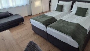 A modern bedroom with a large bed, a wooden desk, and a chair.