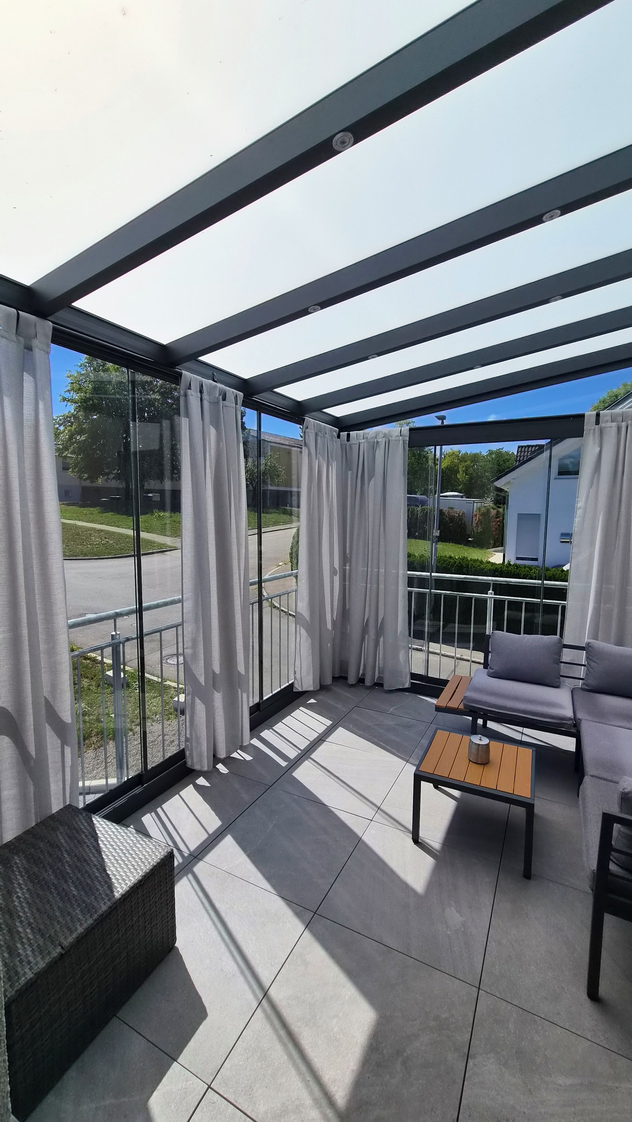 Un espace extérieur aménagé, abrité, avec un canapé, une table et un banc en osier.