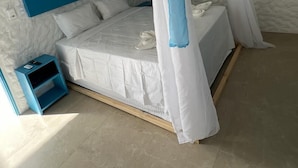 A bedroom with a canopy bed, a blue nightstand, and a white headboard. - KEFI POUSADA (Maragogi)