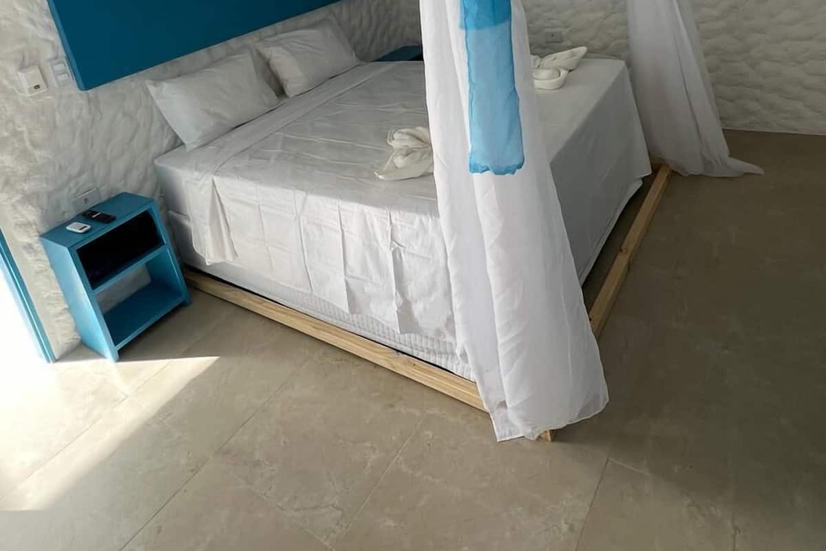 A bedroom with a canopy bed, a blue nightstand, and a white headboard.
