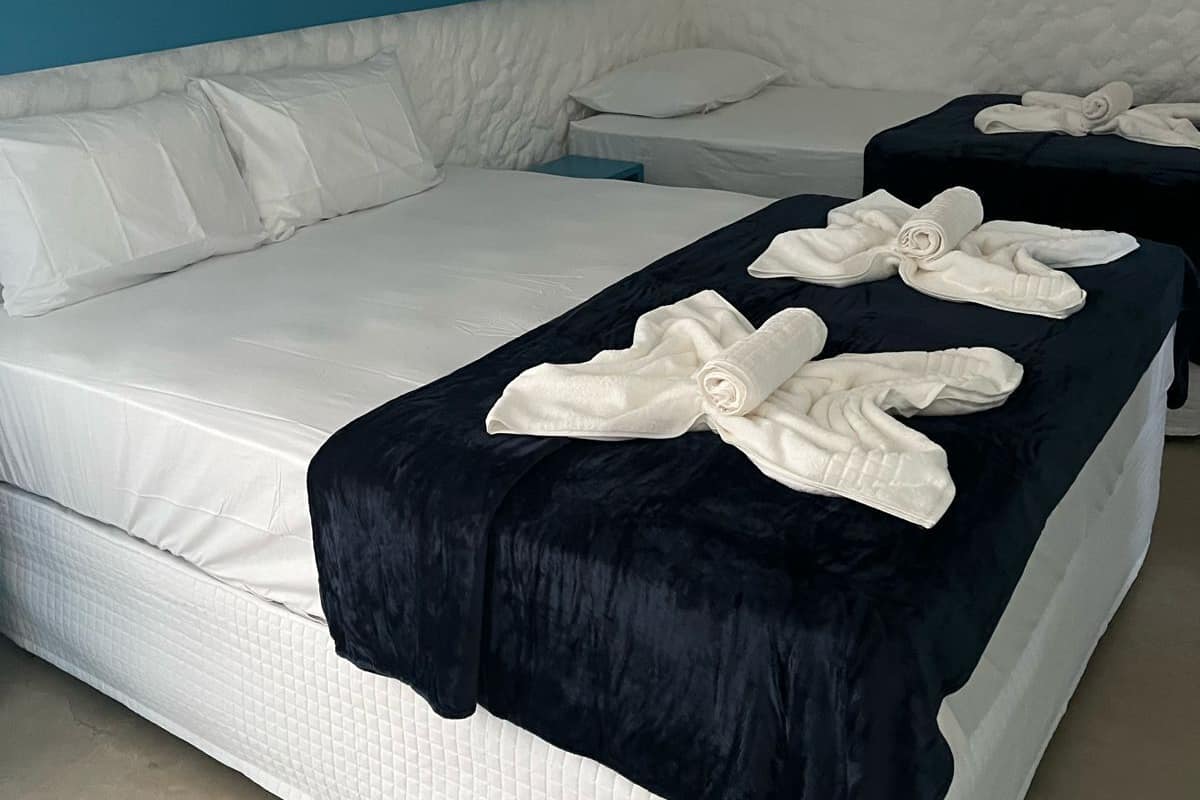 A hotel room with a large bed, a smaller bed, and a desk. There are towels on the beds.