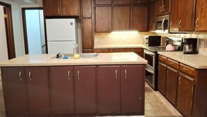 A kitchen with wooden cabinets, a stainless steel refrigerator, a microwave, and an oven. - Lawton Creekside Villa,7 bedrooms, 3 bathrooms,8 beds,beautiful  neighborhood  (Lawton)