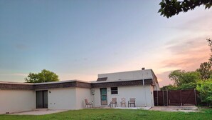A single-story house with a flat roof, a front door, and a small porch with four chairs. - Lawton Creekside Villa,7 bedrooms, 3 bathrooms,8 beds,beautiful  neighborhood  (Lawton)