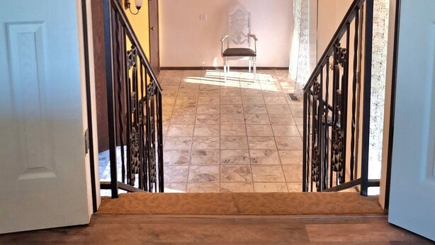 A staircase leading to a second floor with a chandelier, a framed picture on the wall, and a chair. - Lawton Creekside Villa,7 bedrooms, 3 bathrooms,8 beds,beautiful  neighborhood  (Lawton)