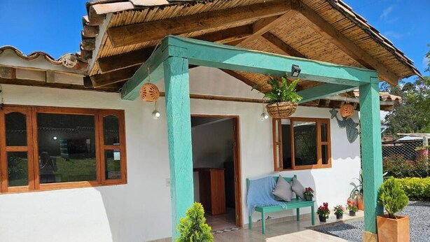Ein Gebäude mit überdachter Veranda, einer Bank und Kübelpflanzen.
