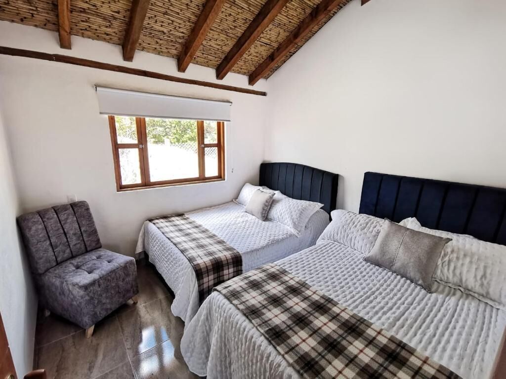 Una camera da letto con due letti, una sedia e una finestra.