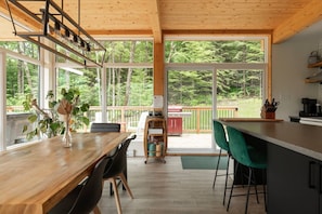 A modern kitchen with large windows, a dining area, and a bar.