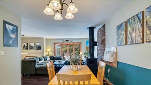 A dining area with a wooden table and chairs, a chandelier, and a brick wall with framed pictures. - Lakeview Getaway: Casino Room, Hot Tub, Gazebo (Tobyhanna)