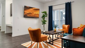 Ein modernes Wohnzimmer mit einer Couch, Sesseln, einem Couchtisch und einem Gemälde an der Wand.