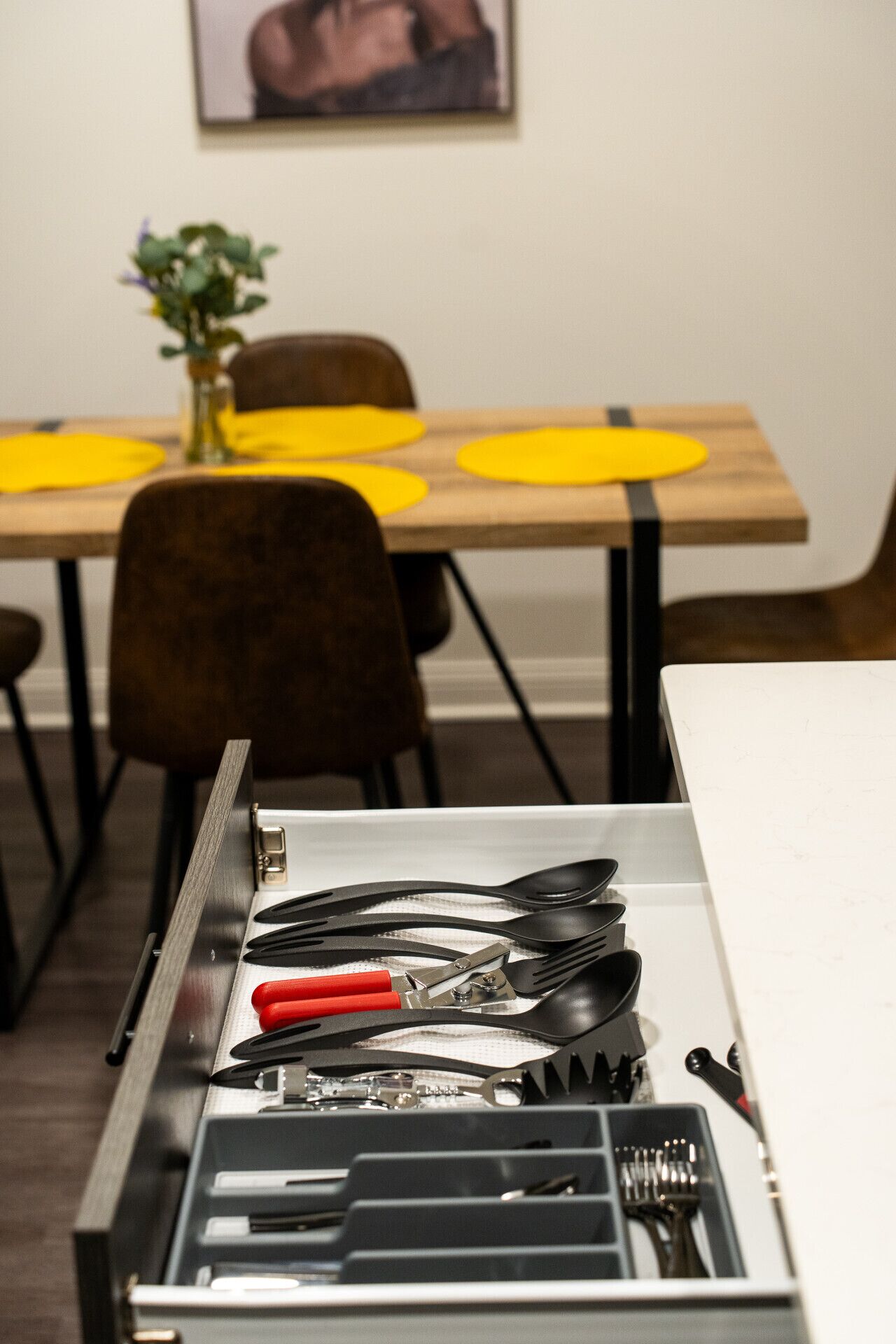 A drawer with various utensils and a laptop.