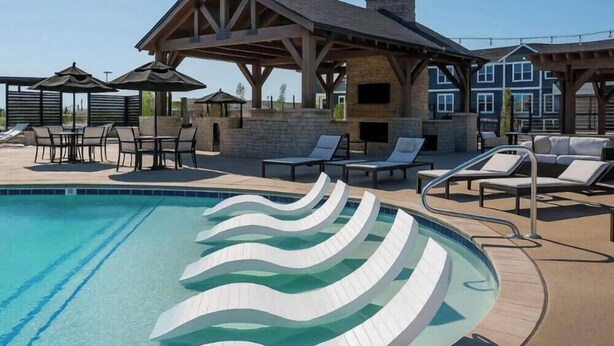 Una piscina con escalones blancos ondulados, sillas de descanso y una zona de estar cubierta.