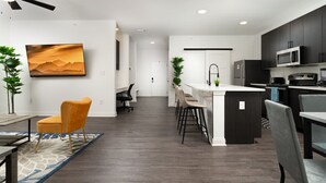 Una cocina moderna con armarios oscuros, una isla central y un comedor con mesa y sillas.