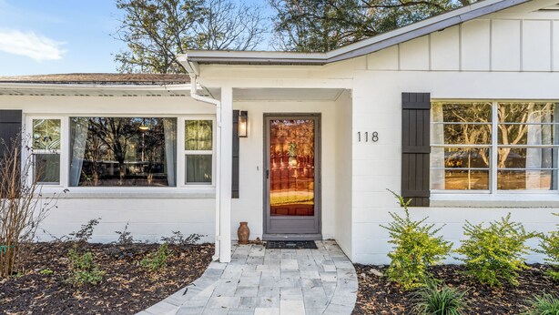 A modern house with a white exterior, a stone pathway leading to the entrance, and a number 118 on the door. - Gator Grove (Gainesville)