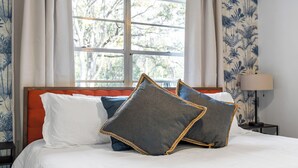 A neatly made bed with white and blue bedding, a red headboard, and decorative pillows. - Gator Grove (Gainesville)