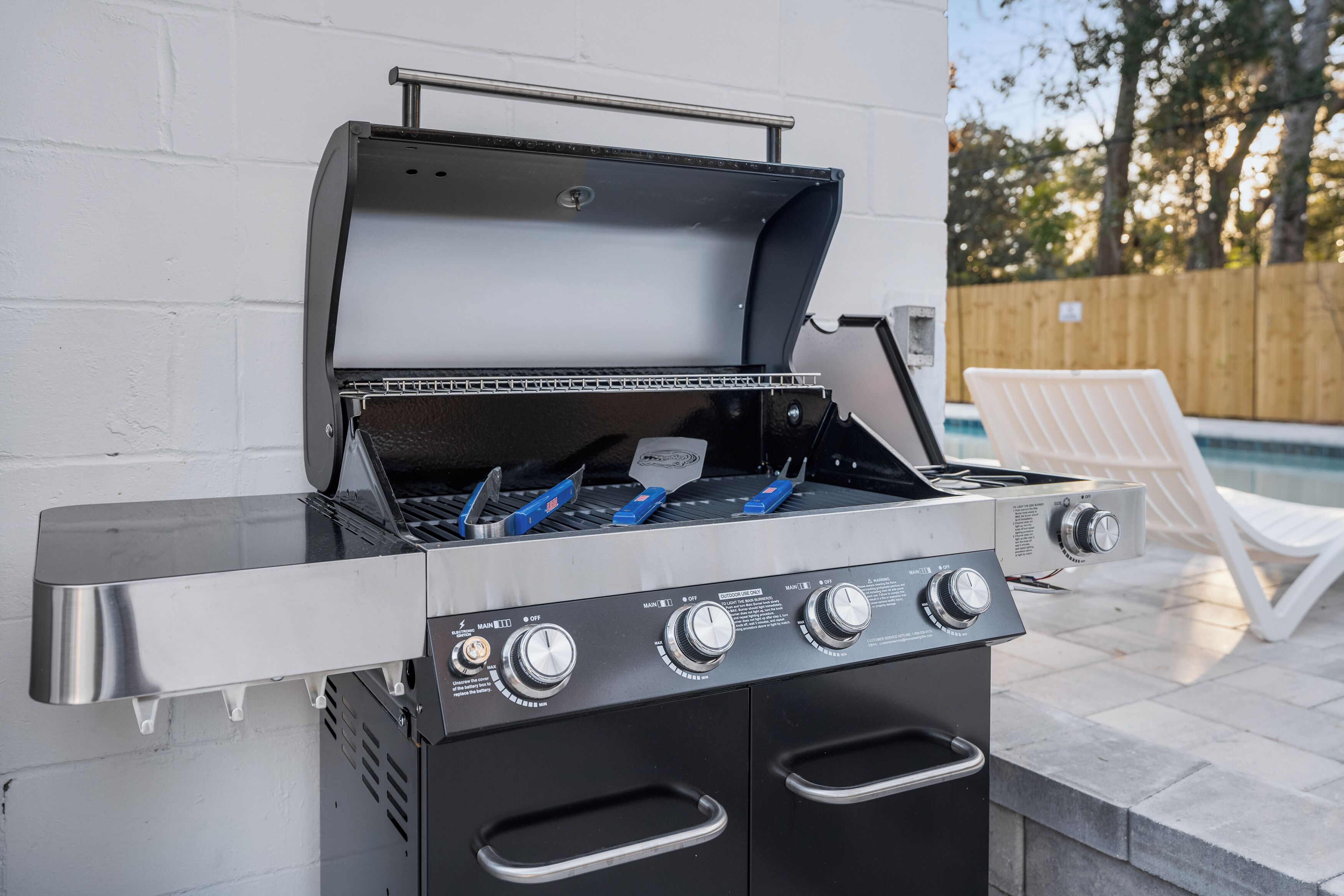 An outdoor grill with a metal frame, control knobs, and a lid.