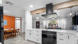 A modern kitchen with white cabinetry, a built-in oven, and pendant lighting. - Gator Grove (Gainesville)