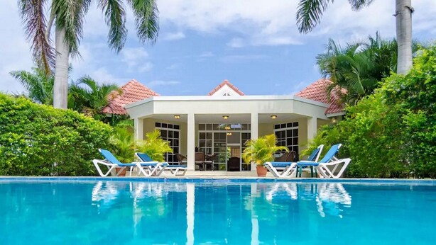 A poolside area with lounge chairs and a covered seating area. - Moradia com piscina privada em residência fechada, totalmente equipada (Sosúa)