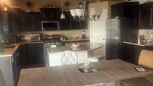 Una cocina moderna con armarios oscuros, electrodomésticos de acero inoxidable y una isla central con asientos.