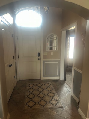 A hallway with a white door, a small window, and a patterned rug.