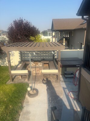 A covered patio area with a pergola, outdoor seating, and a fire pit.