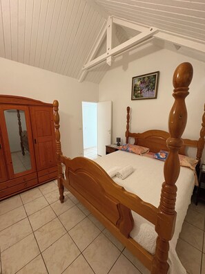 Un dormitorio con una cama con dosel de madera, un armario y una puerta que da a otra habitación.