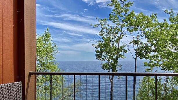 A balcony with a wicker chair and a view of the sea.