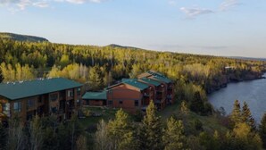 A lodge with multiple buildings, surrounded by dense forest and a river.