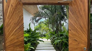 Una puerta de madera con vistas a un sendero de piedra que conduce a un jardín exuberante.
