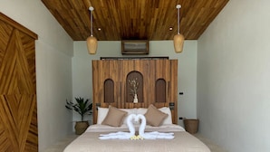Amplia habitación con una cama grande, cabecera de madera y un arreglo decorativo de toallas con forma de cisne.